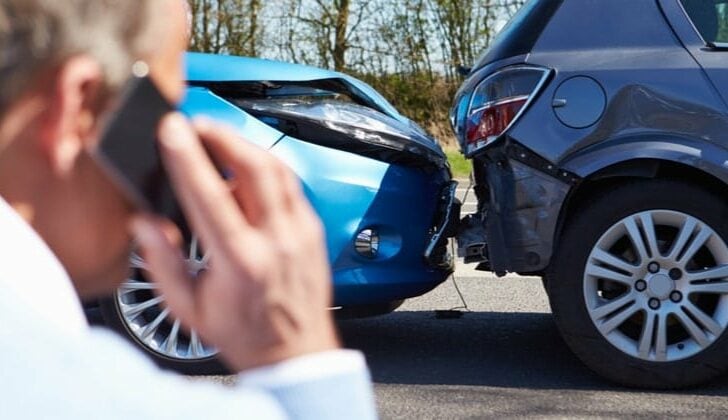 Man calling insurance company after a rear end collision in an SUV