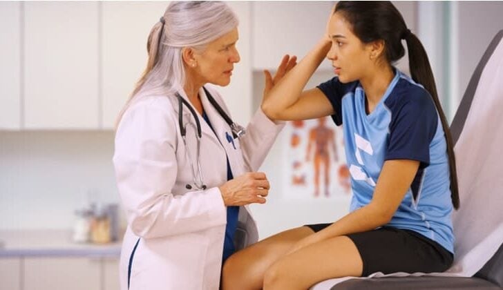 Female student athlete visiting doctor after injury