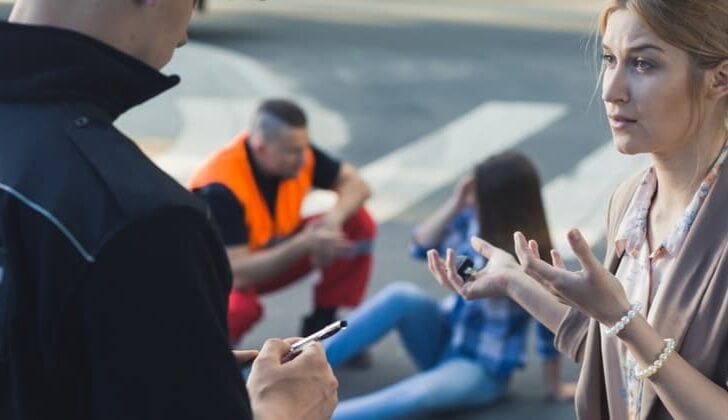 Female car accident witness speaking with law enforcement officer