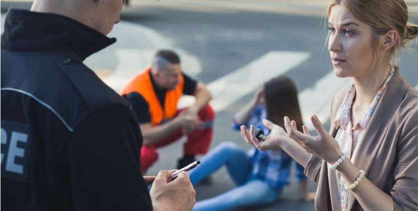 Female car accident witness speaking with law enforcement officer