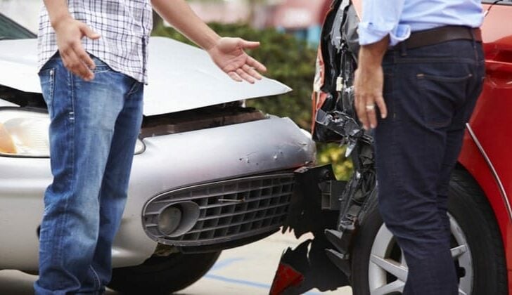 Two men arguing in front of their vehicles after a rear-end collision