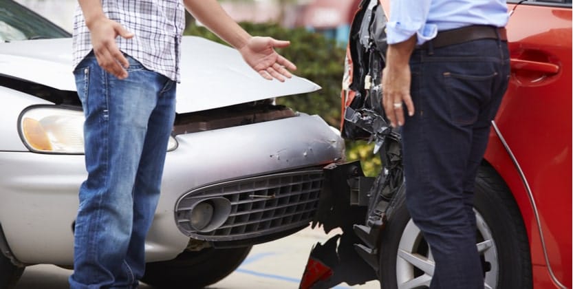 Two men arguing in front of their vehicles after a rear-end collision