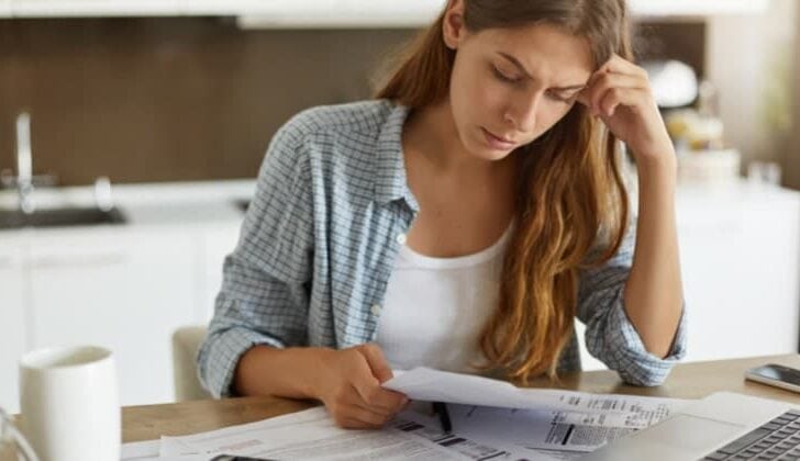 Emotional victim of personal injury victim sitting at the kitchen table and reviewing medical bills