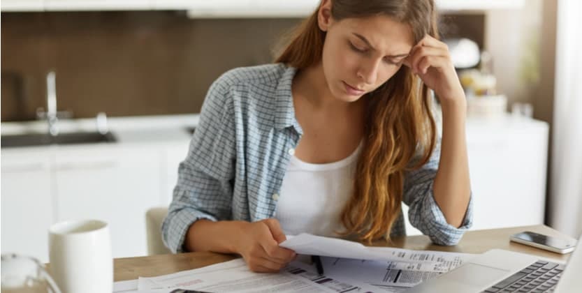 Emotional victim of personal injury victim sitting at the kitchen table and reviewing medical bills