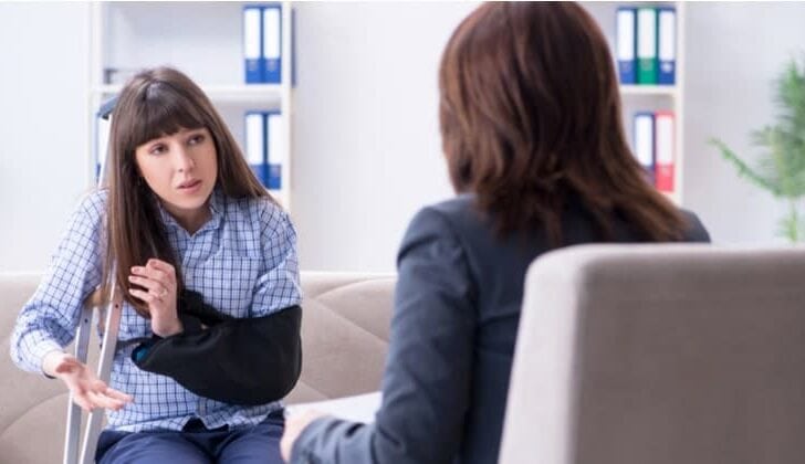 Young woman injured from a slip and fall sits in her attorneys office on the couch asking questions about her case