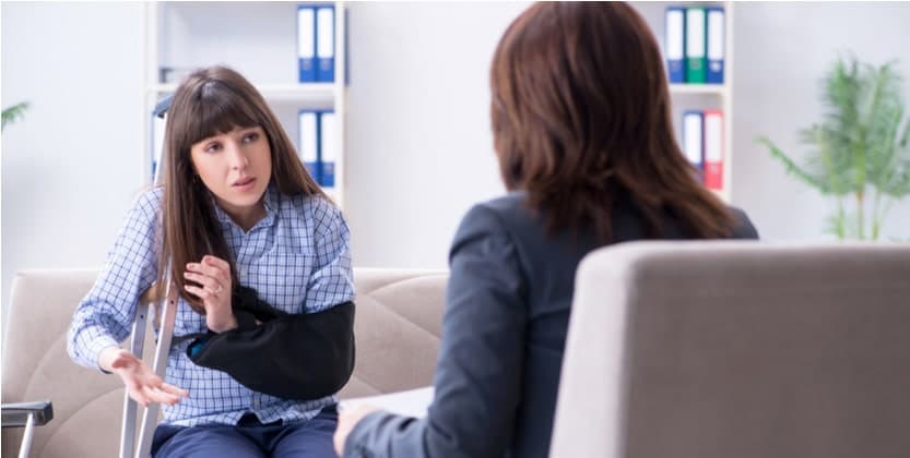 Young woman injured from a slip and fall sits in her attorneys office on the couch asking questions about her case