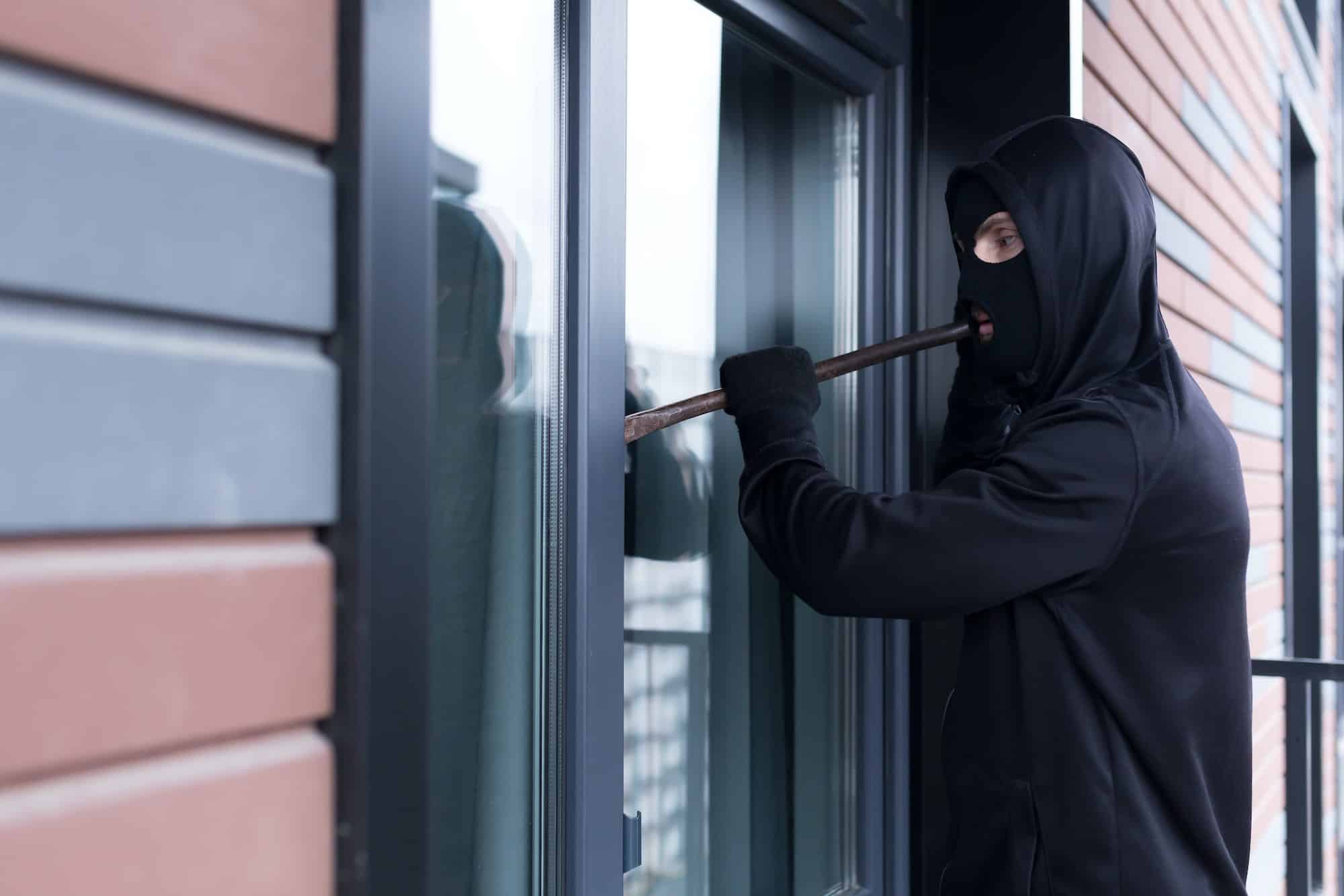 A burglar man tries to break the door lock and get into the apartment for robbery