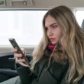 girl in warm clothes with a mobile phone in a car salon