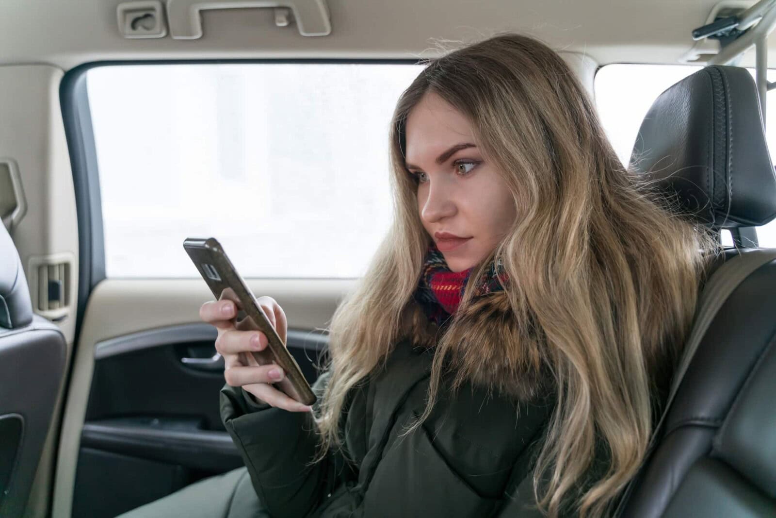 girl in warm clothes with a mobile phone in a car salon