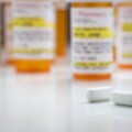 Non-Proprietary Medicine Bottles and Large Pills on Reflective Surface With Grey Background.