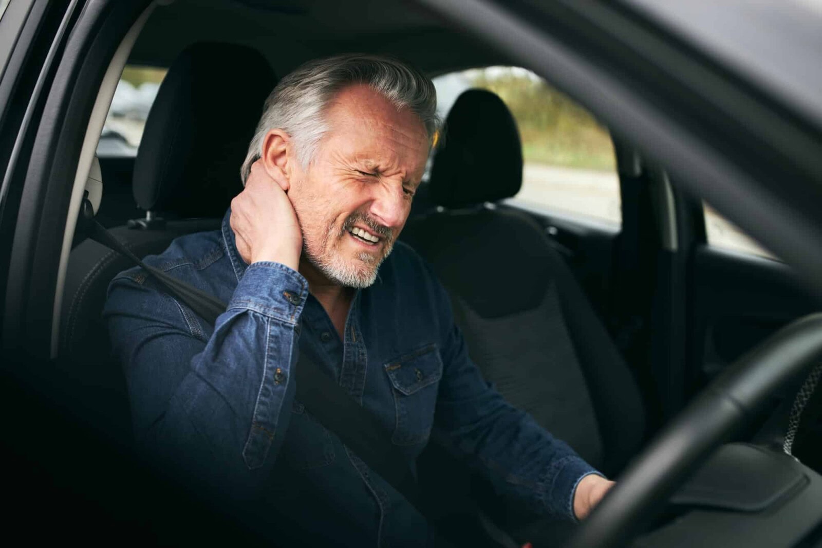 Senior Male Driver Inside Car After Road Traffic Accident Suffering From Whiplash Injury