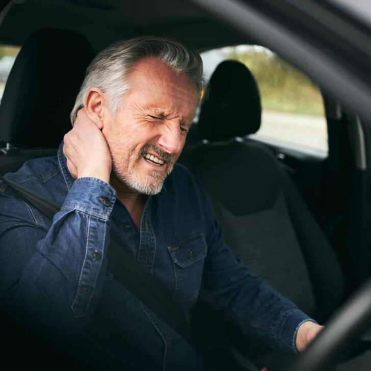 Senior Male Driver Inside Car After Road Traffic Accident Suffering From Whiplash Injury