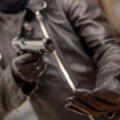 Thief gloved hand holding a pistol aiming, closeup view. Armed robbery concept