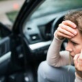 Young woman in the damaged car after a car accident, making a phone call.