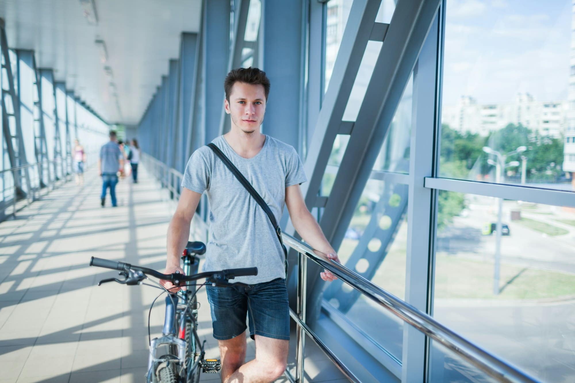 Handsome bicyclist standing on bridge