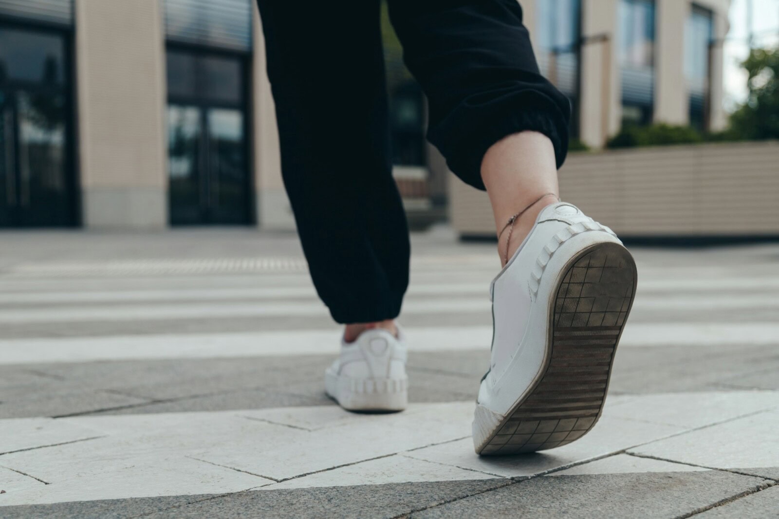 Legs of a girl in White Leather Sneakers Crosses the Street on a Pedestrian Crossing