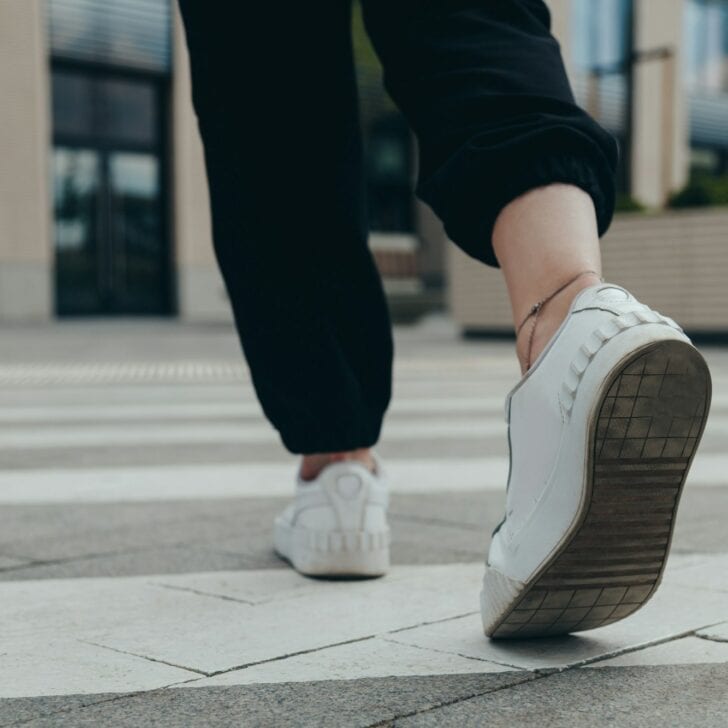 Legs of a girl in White Leather Sneakers Crosses the Street on a Pedestrian Crossing
