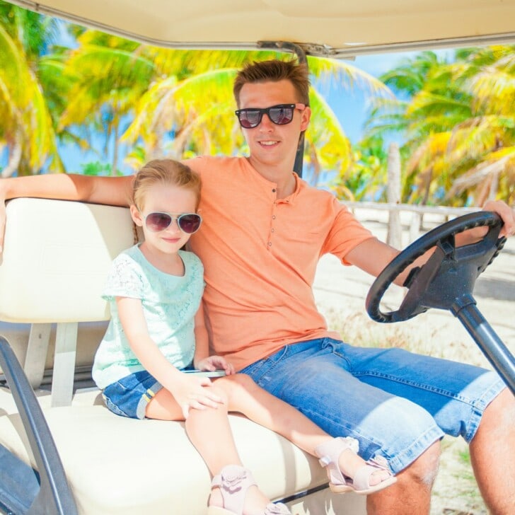 Little girl with father golf cart on tropical beach