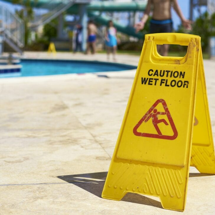 Yellow wet floor caution sign in summer day, closeup