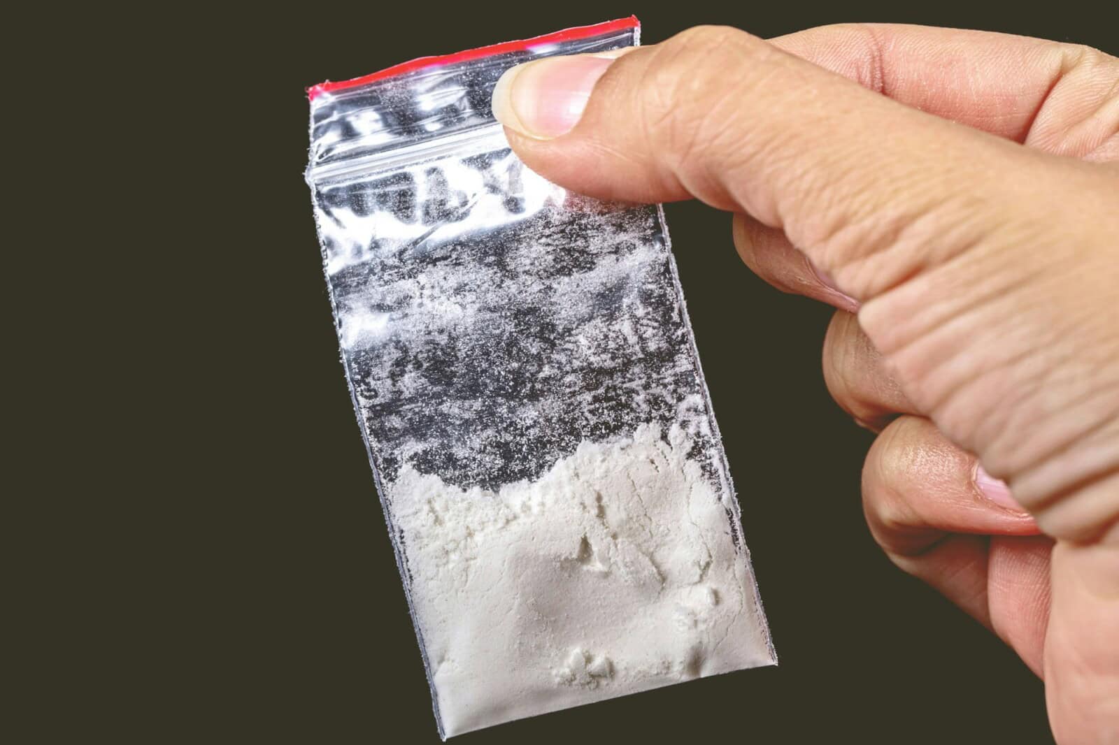 Closeup of a hand of a person holding a small package of white powder