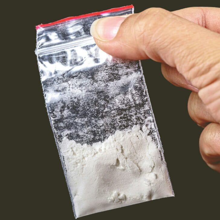 Closeup of a hand of a person holding a small package of white powder
