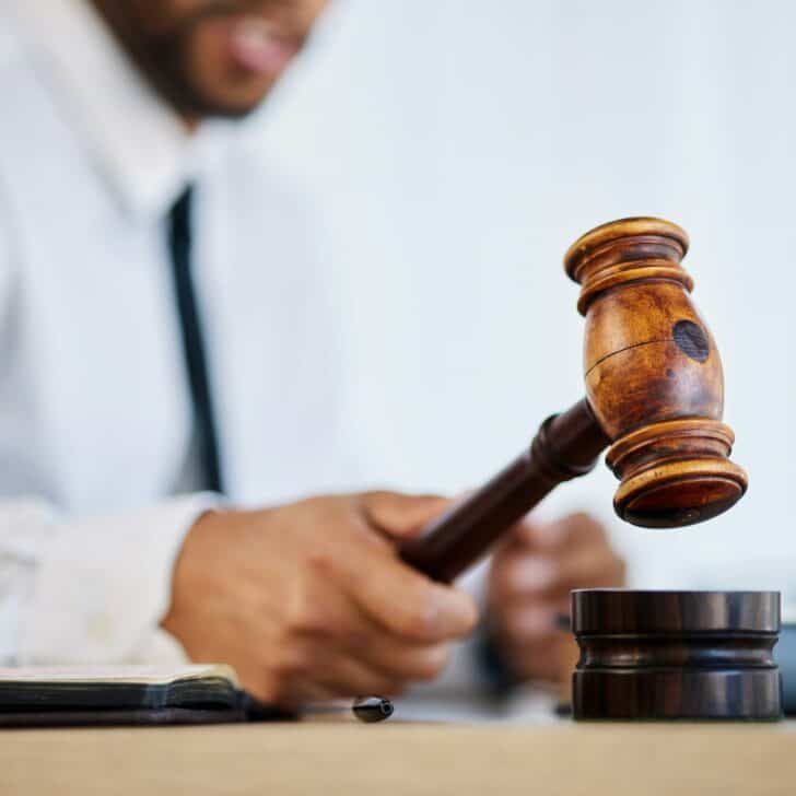 Hand, gavel and a man judge in court for order during a verdict in a criminal case or trial closeup