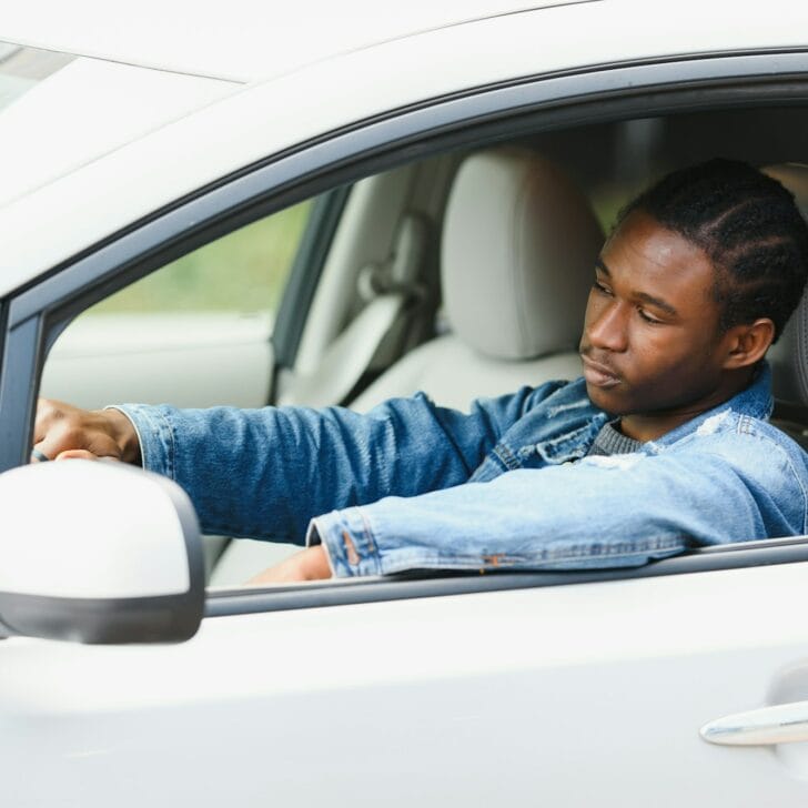 Male Teenage Driver Looking Out Of Car Window