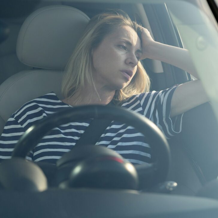 Annoyed tired female on driver seat in car frustrated with heavy traffic jams suffer fatigue stress