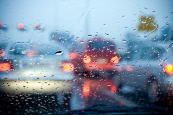 car driving in a rain storm with blurred red lights 600x400