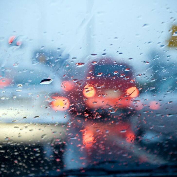Car driving in a rain storm with blurred red lights