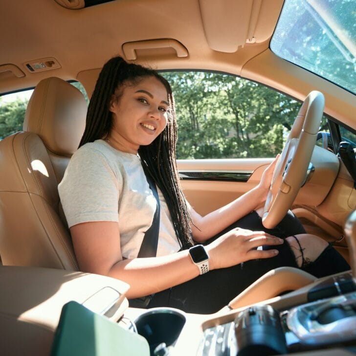 Cheerful automobile driver seated at steering wheel