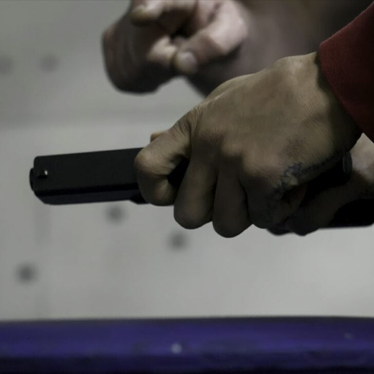 Trainer is teaching man to shoot a gun close up. Close up of male hands with a gun, man trains to