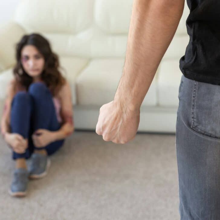 Victim, domestic violence and abuse concept - man threatening with fist to crying woman on floor