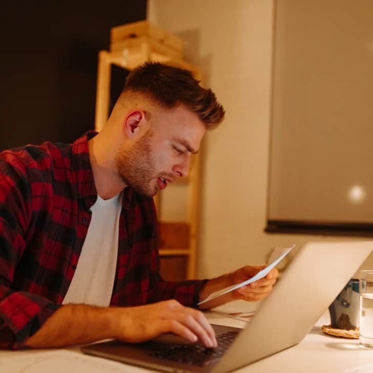 a young boy pays bills using a laptop. A young businessman works overtime from home.