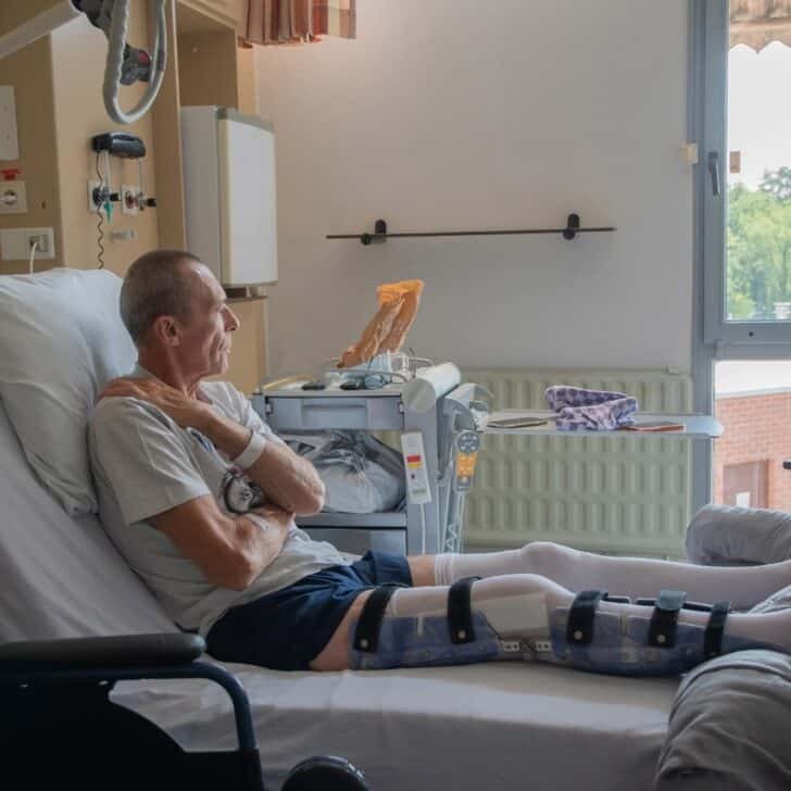 man with broken leg in an orthosis on bed in a clinic after an accident and a fracture of the femur