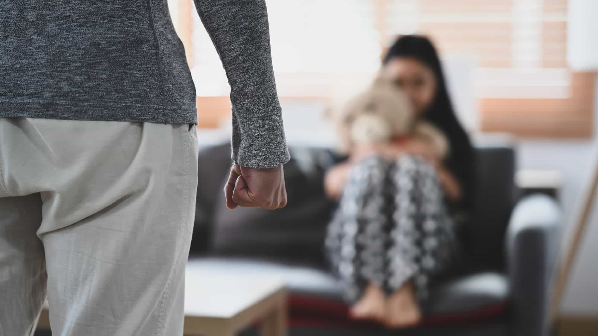 Aggressive man with clenched fist threatens to hit scared little girl.
