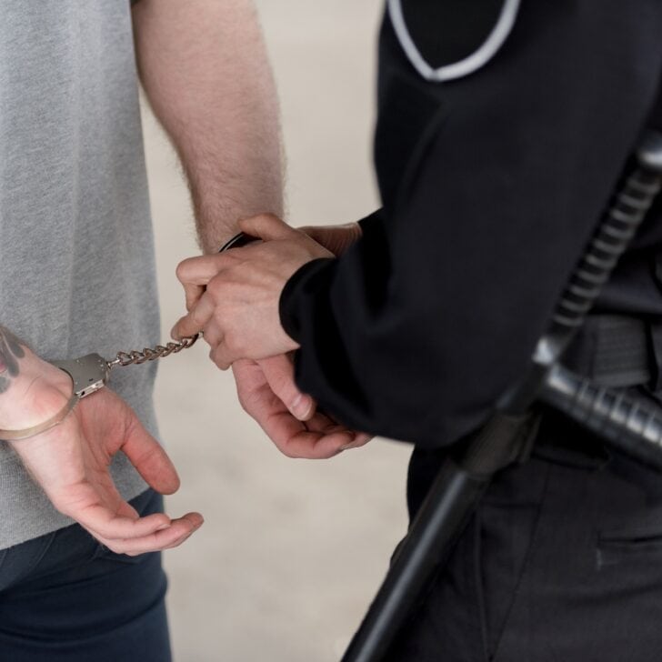 cropped shot of policewoman with truncheon handcuffing bandit