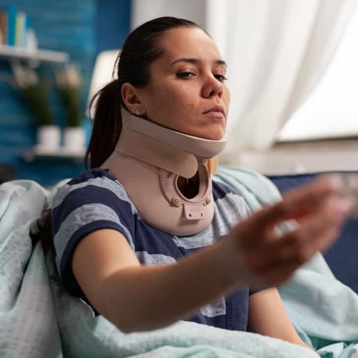 Woman with sickness and cervical foam collar on couch