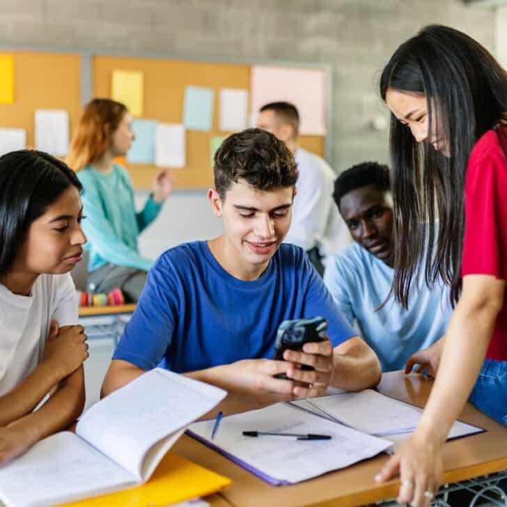 Multiracial group of student friends watching social media content on smartphone