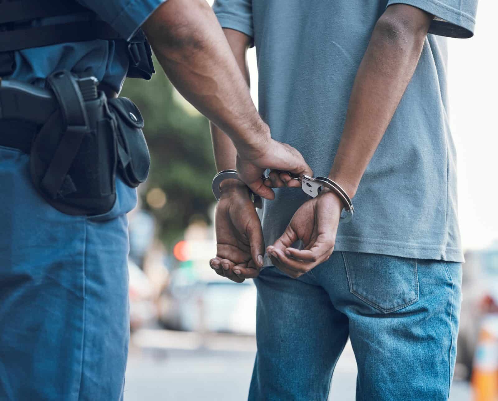 Handcuffs, police and hands of police man with criminal in city for justice, crime or corruption. I