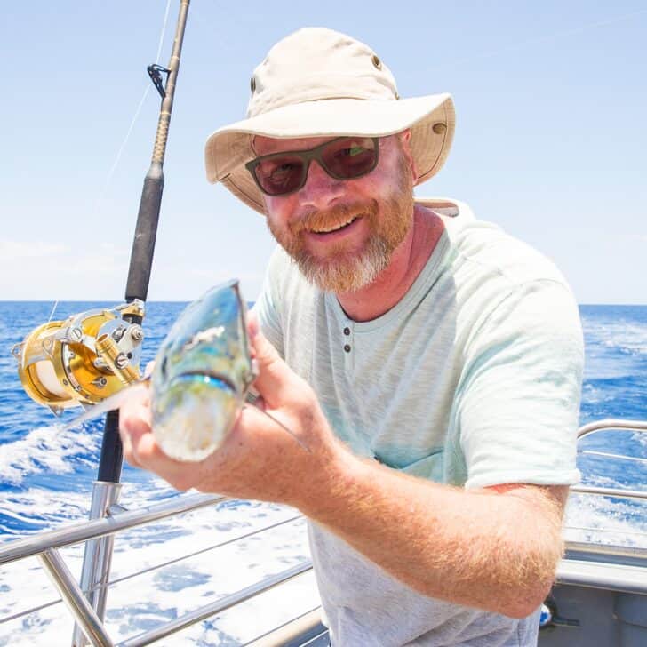 Man holding fresh caught Mahi Mahi on ocean boat