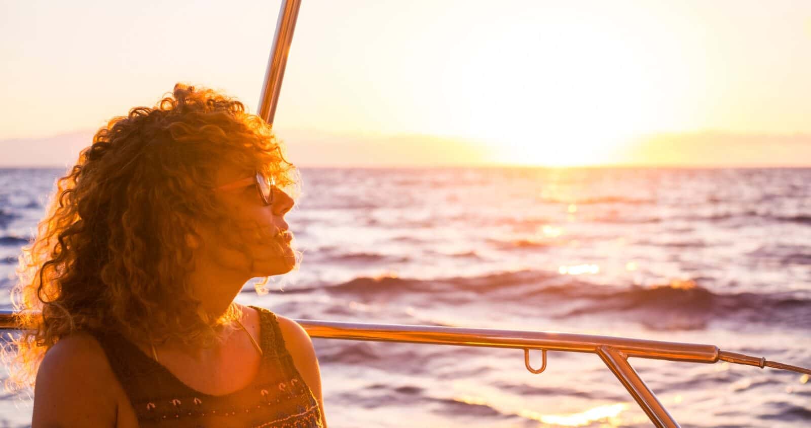 Portrait of a beautiful adult caucasian woman enjoying the sunset on the boat