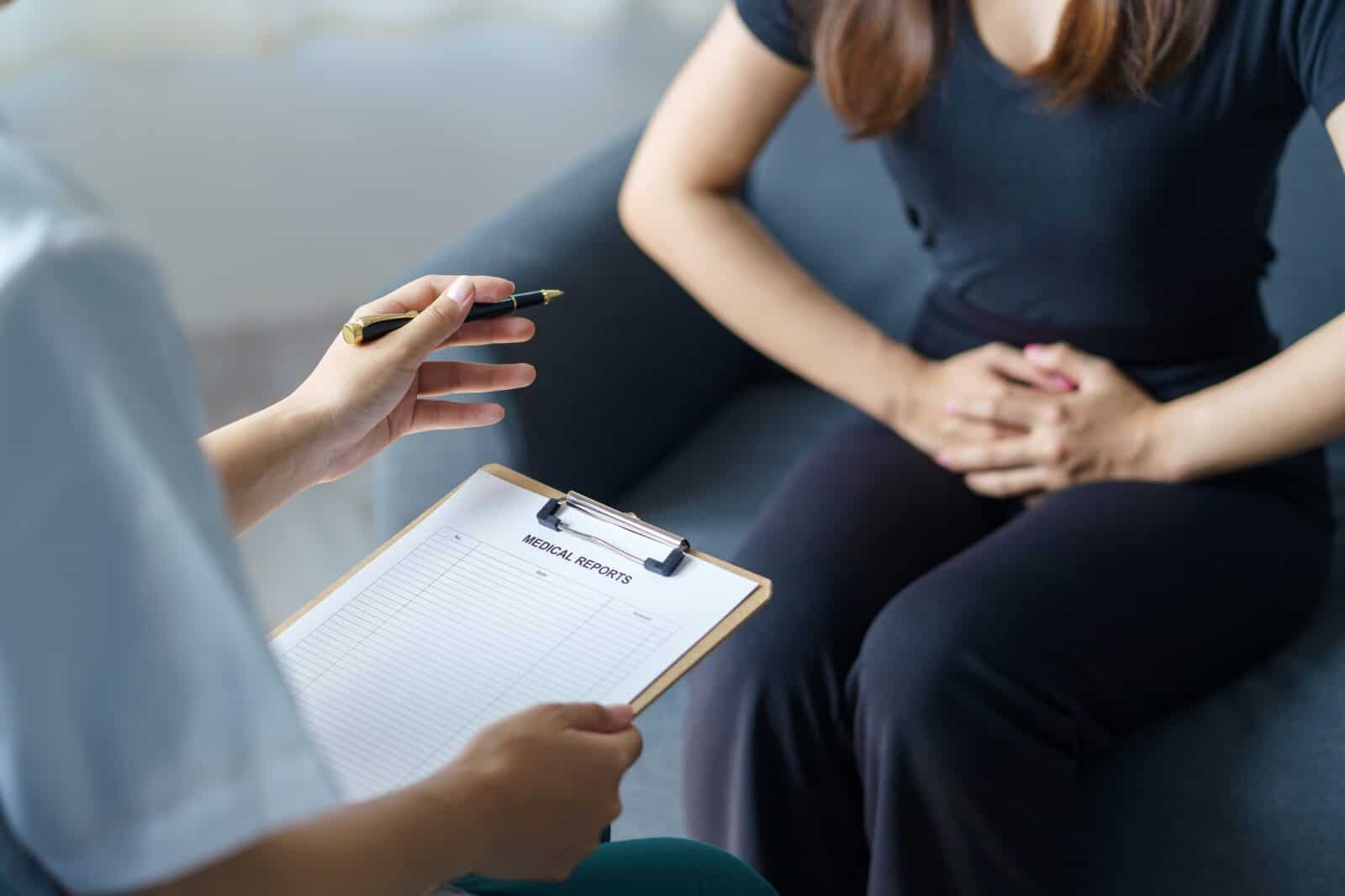 The female patient explains the abdominal pain to the doctor about the cause of the symptoms