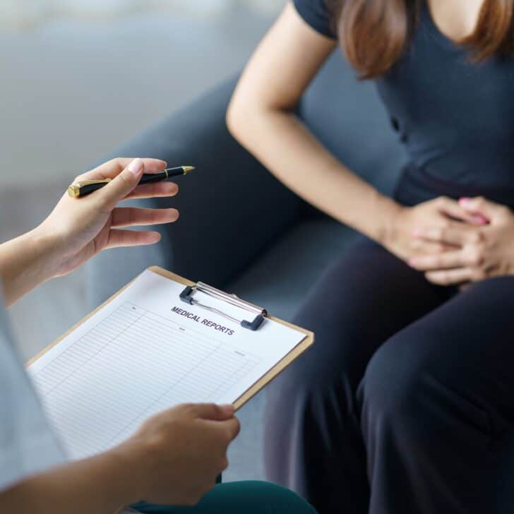 The female patient explains the abdominal pain to the doctor about the cause of the symptoms