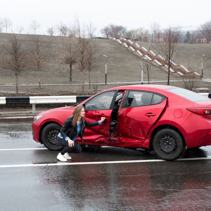 Woman sits near a broken car after an accident. call for help. car insurance.